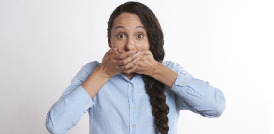 woman with a long braid covering her mouth with both hands